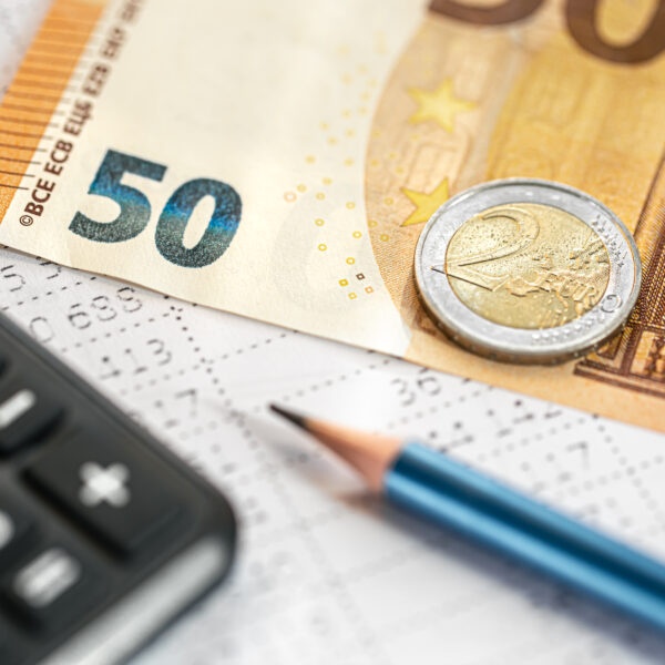 Taschenrechner, Geld und eine Tabelle im Hintergrund.